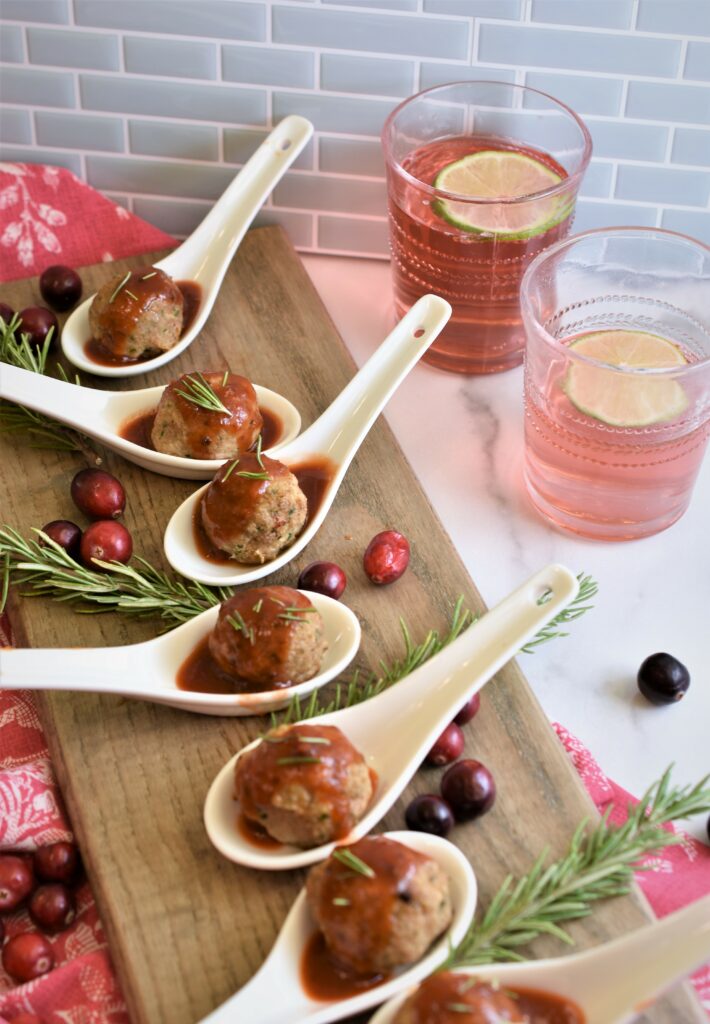 cocktail turkey meatballs with chipotle cranberry glaze in porcelain soup spoons on wood board