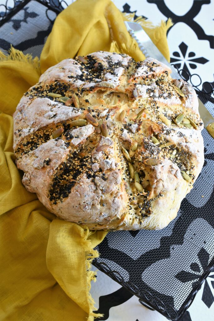 crazy Dutch oven bread on cooling rack with yellow napkin on black and white Spanish tiled countertop 