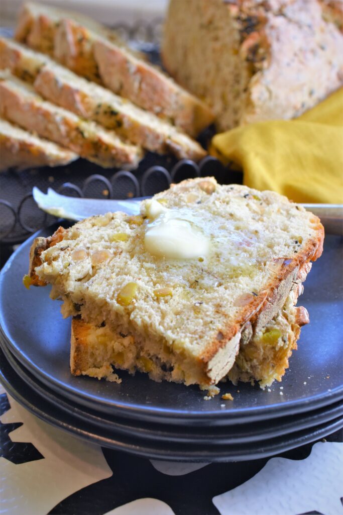 fresh baked bread with butter melting on slices on black plates