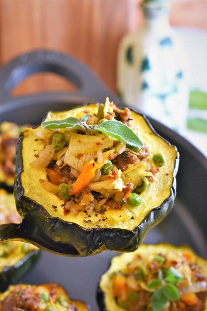 up close gold serving spoon with small vegetable stuffed acorn squash