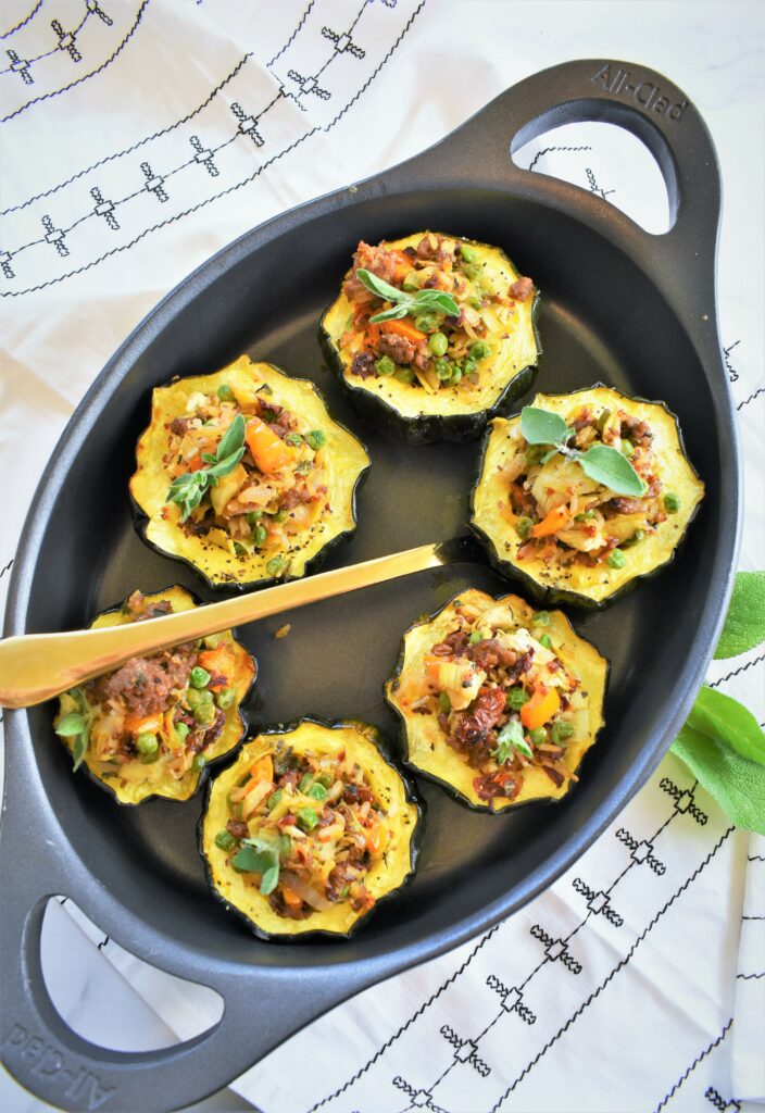 overhead shot of black oval casserole filled with Beyond Italian style stuffed acorn squash with quinoa 