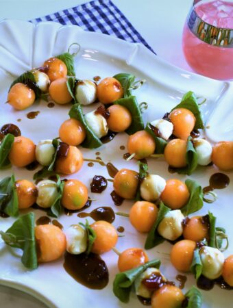 white oval ceramic platter with cantaloupe caprese skewers