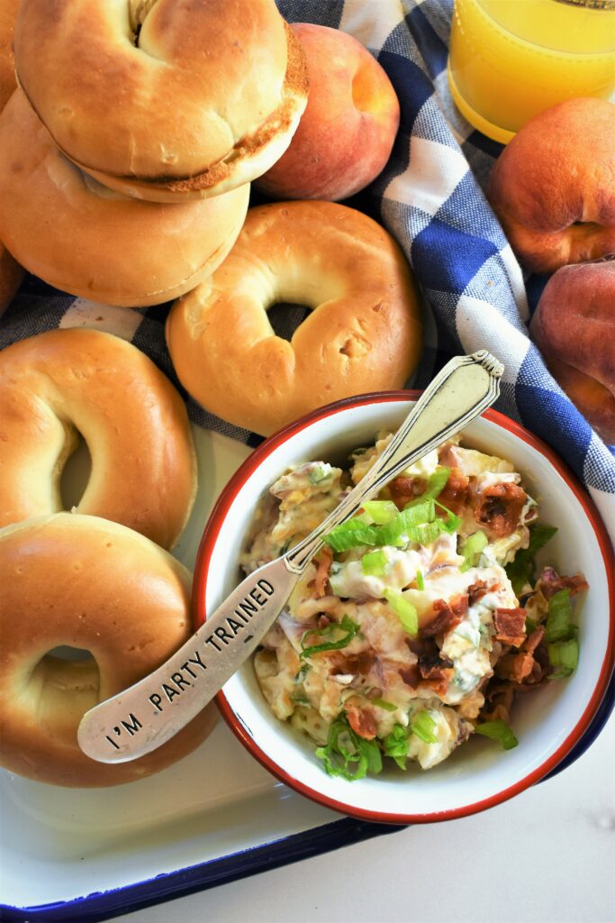 several bagels with blue and white gingham napkin with bowl of spread