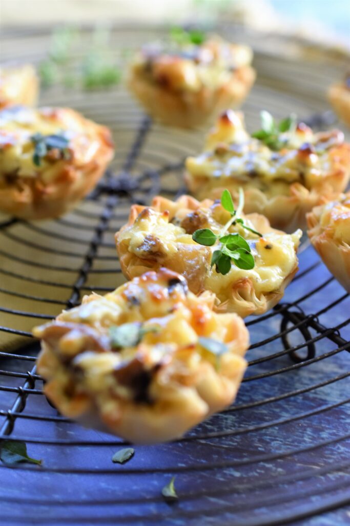 up close shot of several mushroom & gruyere cheese phyllo tartlets on a round wire cooling rack 