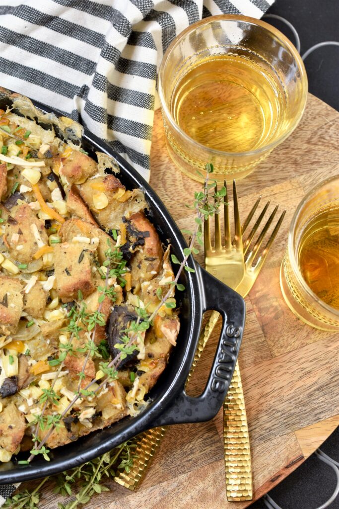 up close overhead shot of casserole with two forks and two glasses of wine