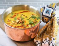 soup in copper pot on wood board on marble countertop