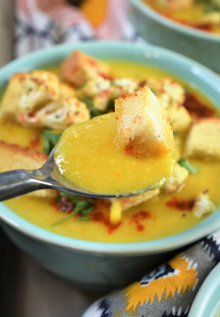 up close shot of spoonful of soup garnished with crouton