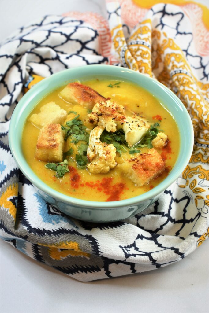 vegan bisque in one sea green bowl with patterned napkin wrapped around it