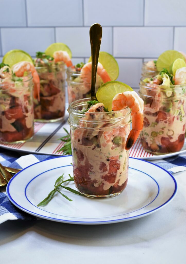 chilled shrimp appetizer in jar on blue and white plate with gold fork