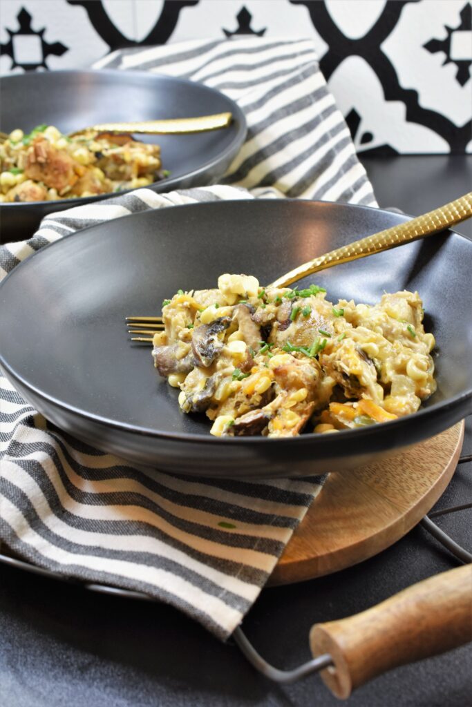 up close shot of two black round ceramic bowls with dinner in them with gold forks on cutting board