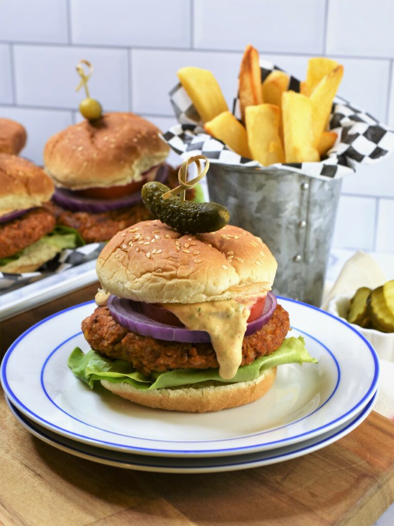 up close image of Chipotle Butternut Squash Burger with Hatch Chile Aioli on two stacked white with blue rimmed plates