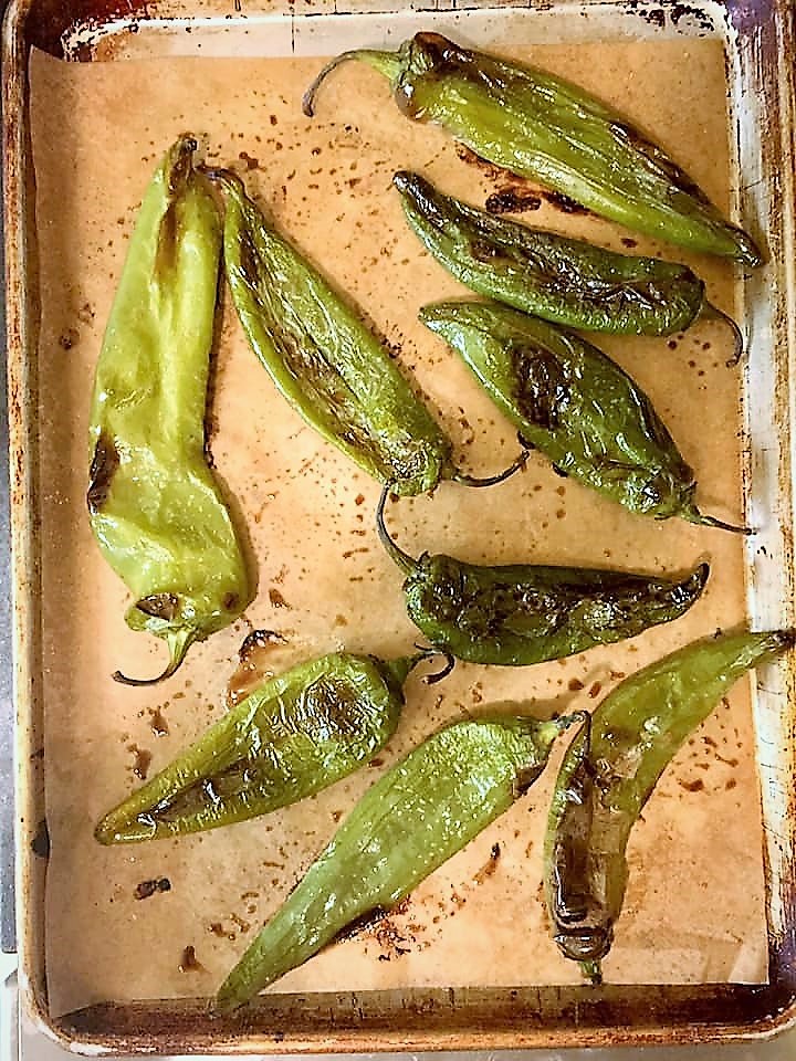 sheet pan with parchment with several roasted hatch chiles right out of the oven