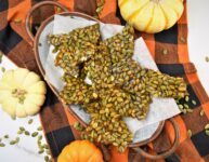 pumpkin seed brittle on oval rustic copper tray on black and orange buffalo plaid napkin with mini pumpkins surrounding