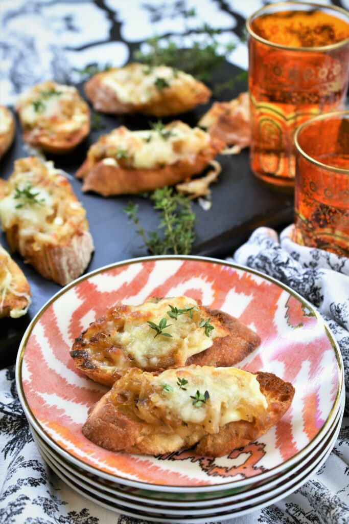 cheesy toasts with thyme on a stack of colorful appetizer plates