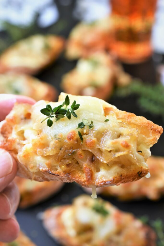 Brandied Caramelized Onion Swiss Crostini holding up close