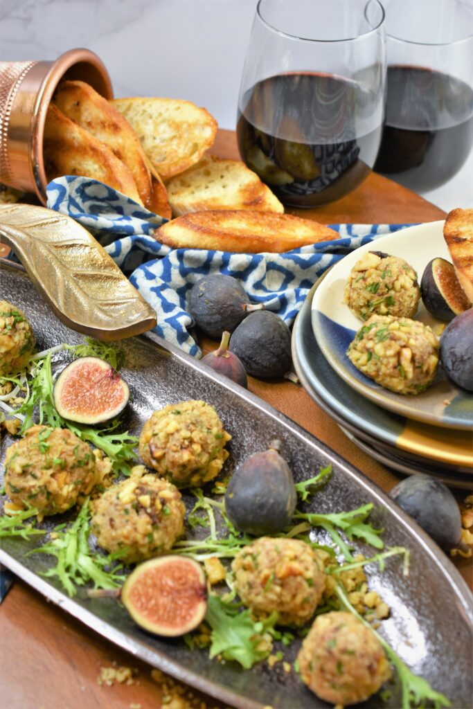 mini nutty cheesy appetizer on metal platter on cutting board with glasses of red wine