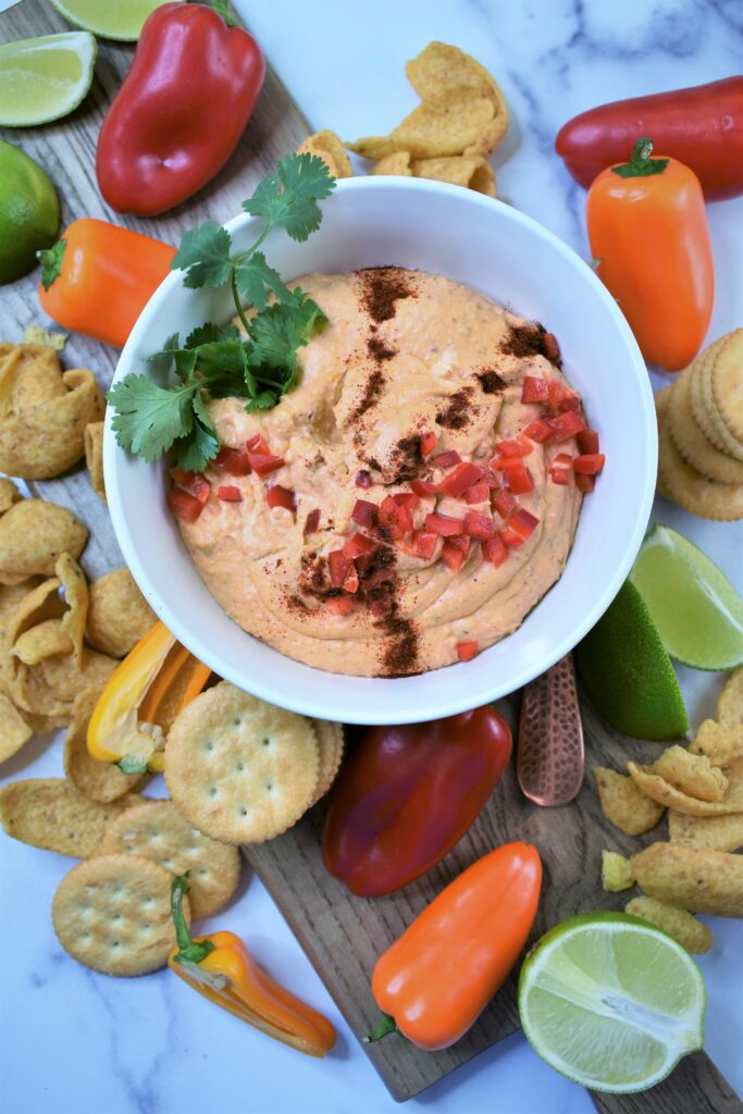chipotle lime cheese dip in bowl garnished with chopped red peppers and cilantro
