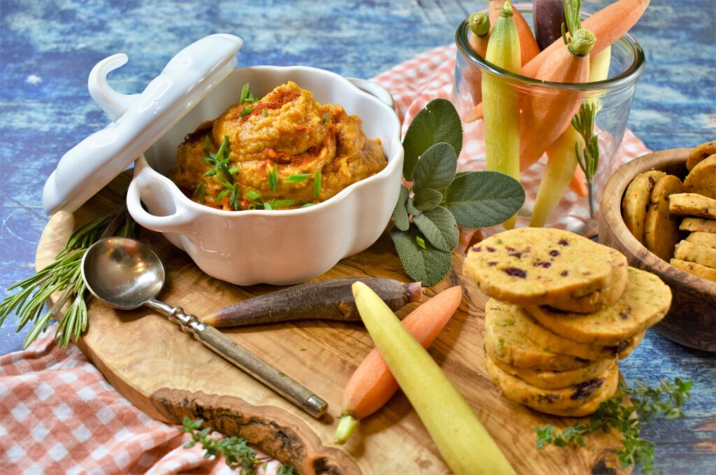 autumnal squash spread display in white ceramic bowl on rustic live edge cutting board with crackers and carrots