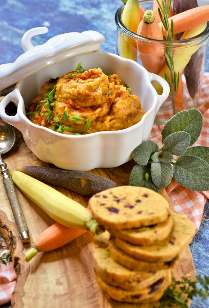 pumpkin white bean dip with herbs in white ceramic pumpkin shaped bowl on cutting board with cranberry pistachio shortbread crackers