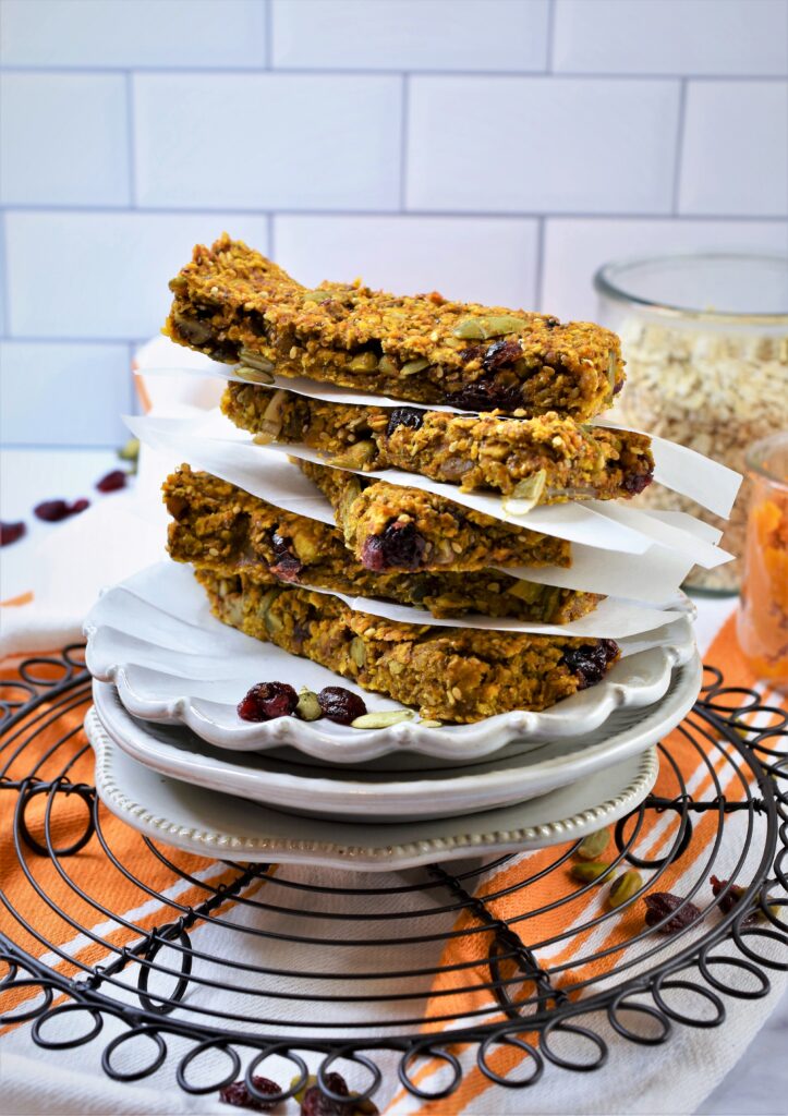 small white round vintage inspired plates stacked with oat breakfast bars on round black wire rack on kitchen towel