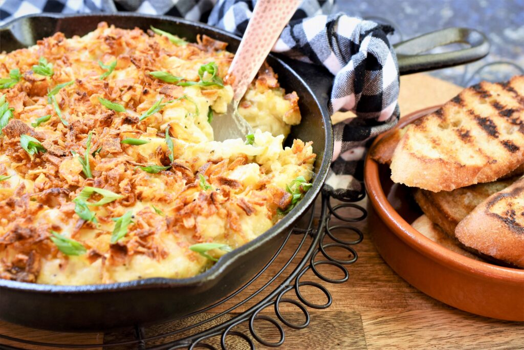 baked onion spread in frying pan on cutting board with grilled toasts