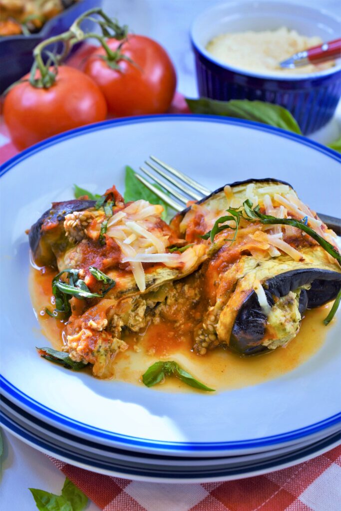 vegan cheese basil stuffed eggplant rollatini on white and blue plate