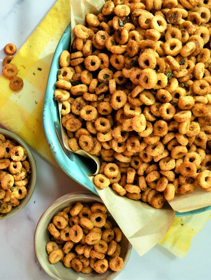 vegan chili cheese cherrios in aqua ceramic bowl with small bowls on white marble countertop