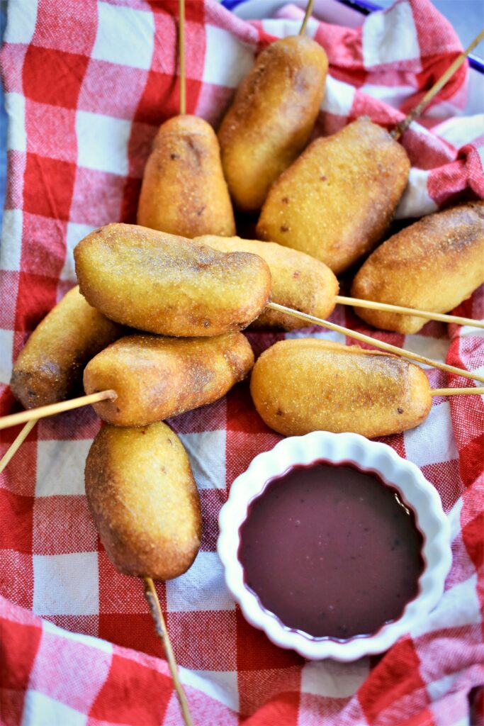 Mini Chipotle Corn Dogs with Blackberry Honey Mustard on red and white checked napkin