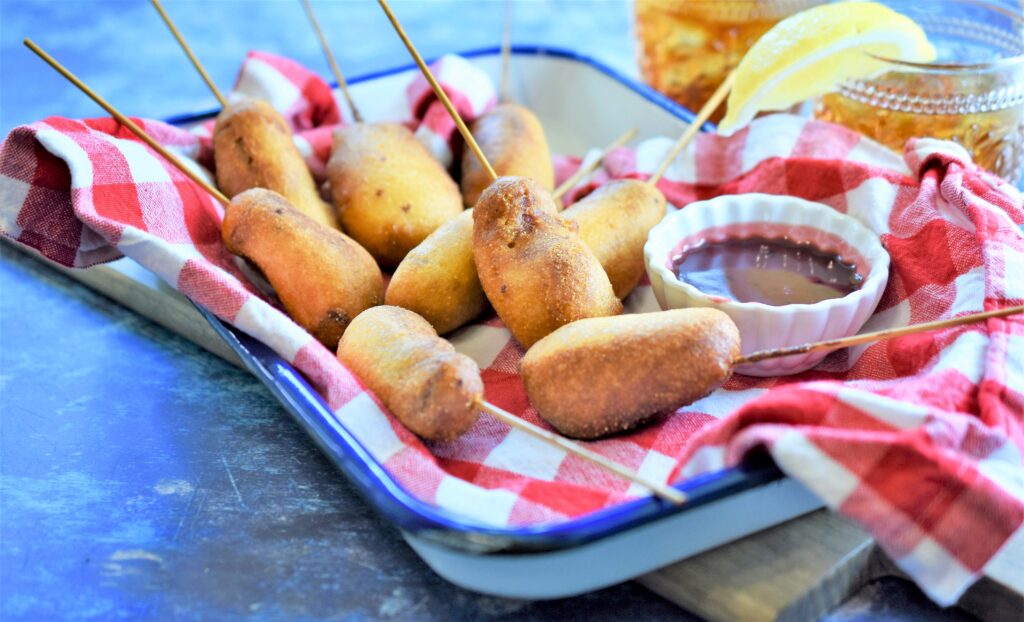 Mini Chipotle Corn Dogs with Blackberry Honey Mustard ready for the Super Bowl on blue and white metal tray with red and white checker napkin